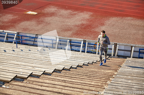 Image of happy young man running upstairs on stadium