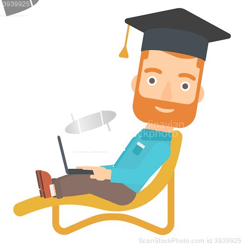 Image of Graduate lying on chaise lounge with laptop.