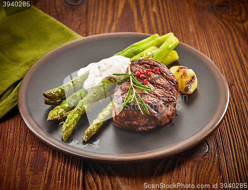 Image of grilled beef steak and asparagus on dark plate