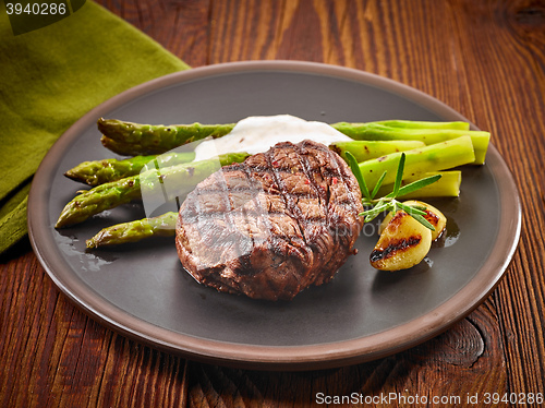 Image of grilled beef steak and asparagus on dark plate