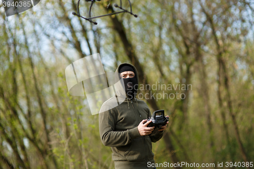 Image of Man in mask operating a drone with remote control.