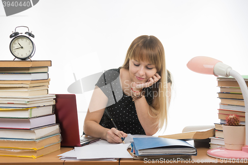 Image of college student smiling engaged at the table cluttered with books in the library