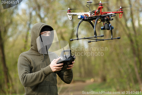 Image of Man in mask operating a drone with remote control.