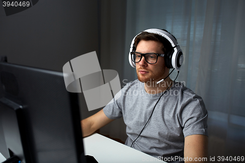 Image of man in headset playing computer video game at home