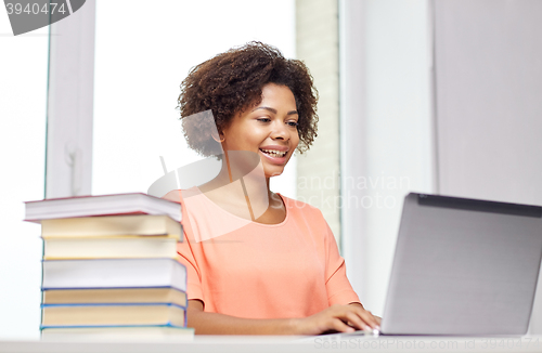 Image of happy african american woman with laptop at home