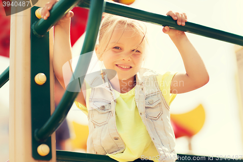 Image of happy little girl climbing on children playground