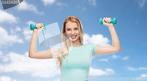 Image of smiling beautiful young sporty woman with dumbbell