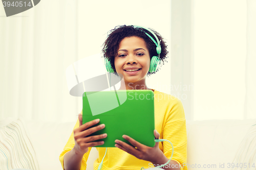 Image of happy african woman with tablet pc and headphones