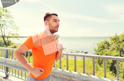 Image of happy man with earphones running outdoors