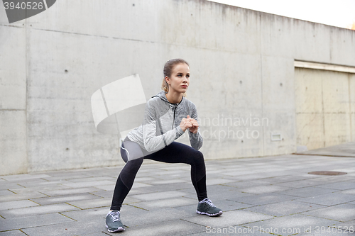 Image of happy woman doing squats and exercising outdoors
