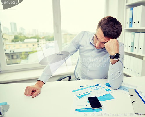 Image of stressed businessman with papers in office