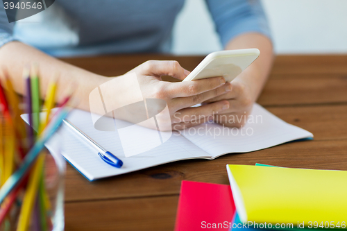 Image of close up of student with smartphone and notebook