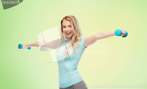 Image of smiling beautiful young sporty woman with dumbbell