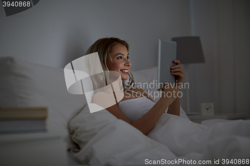 Image of young woman with tablet pc in bed at home bedroom