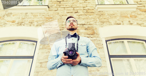 Image of happy young hipster man with film camera in city