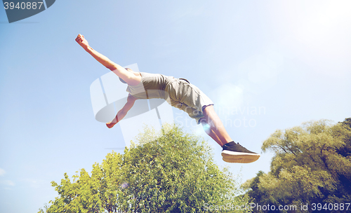 Image of sporty young man jumping in summer park