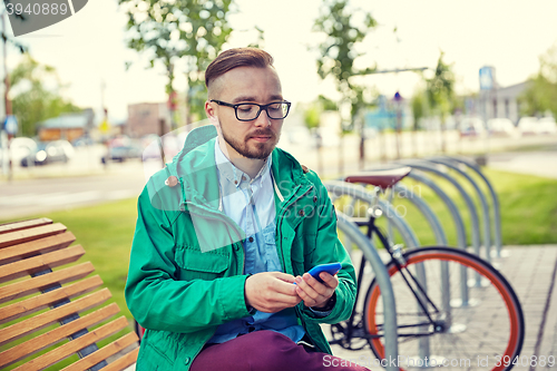 Image of happy young hipster man with smartphone and bike