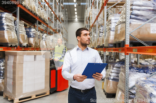 Image of businessman with clipboard at warehouse