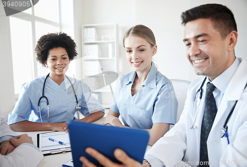 Image of happy doctors with tablet pc meeting at hospital