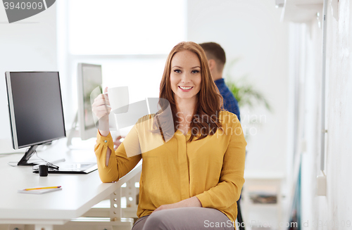 Image of happy woman drinking coffee or tea at office