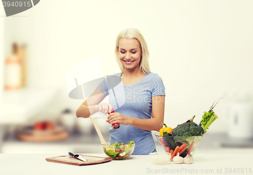 Image of smiling woman cooking vegetable salad on kitchen