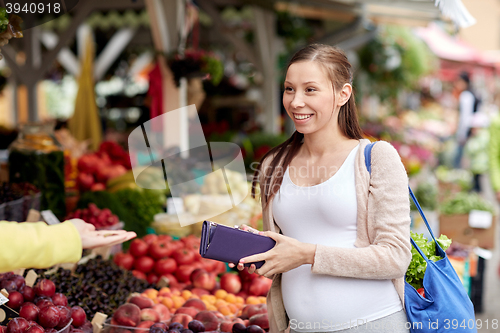 Image of pregnant woman with wallet buying food at market