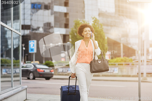 Image of happy woman with travel bag calling on smartphone