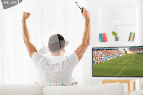 Image of happy man watching football or soccer game on tv