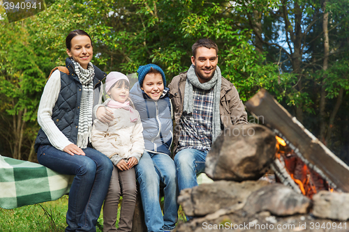 Image of happy family sitting on bench at camp fire