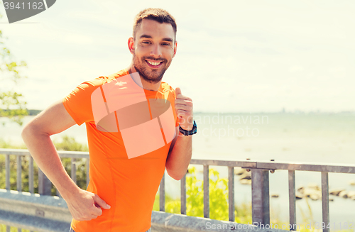 Image of smiling young man running at summer seaside