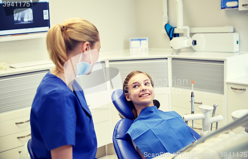 Image of happy female dentist with patient girl at clinic