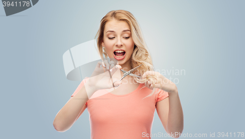 Image of woman with scissors cutting ends of her hair