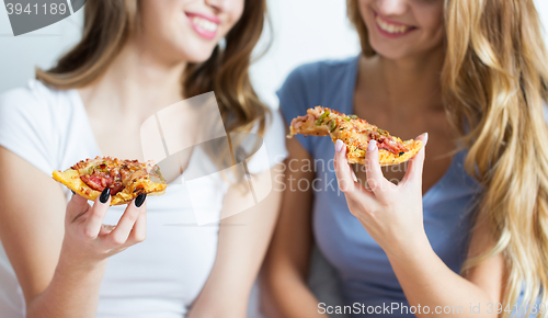 Image of happy friends or teen girls eating pizza at home