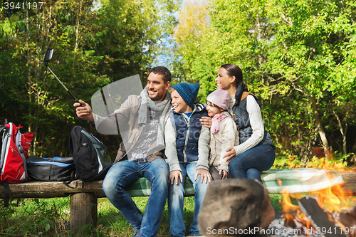 Image of family with smartphone taking selfie near campfire