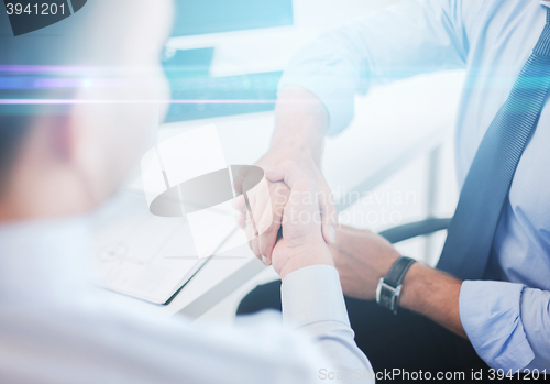 Image of businessmen shaking hands in office