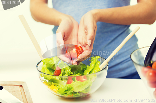 Image of close up of woman cooking vegetable salad at home