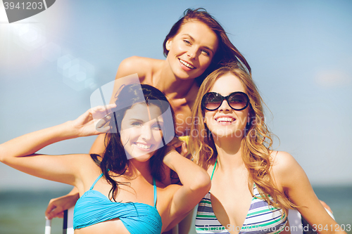 Image of girls sunbathing on the beach chairs