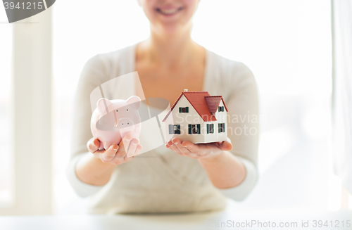 Image of close up of woman with house model and piggy bank