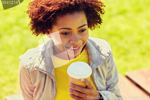 Image of smiling african woman drinking coffee outdoors 