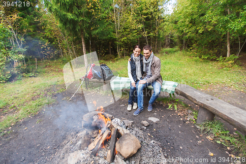 Image of happy couple sitting on bench near camp fire