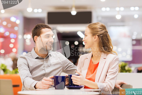 Image of happy couple with shopping bags drinking coffee