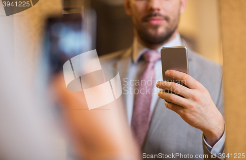 Image of close up of man in suit taking mirror selfie