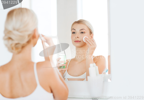 Image of young woman with lotion washing face at bathroom