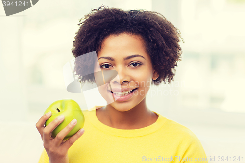 Image of happy african american woman with green apple