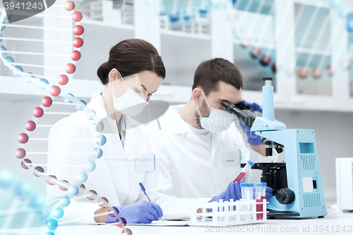 Image of scientists with clipboard and microscope in lab