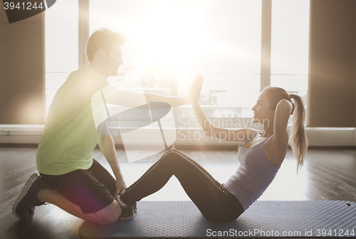 Image of woman with personal trainer doing sit ups in gym