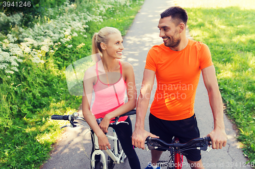 Image of happy couple riding bicycle outdoors