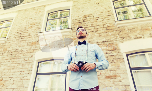 Image of happy young hipster man with film camera in city