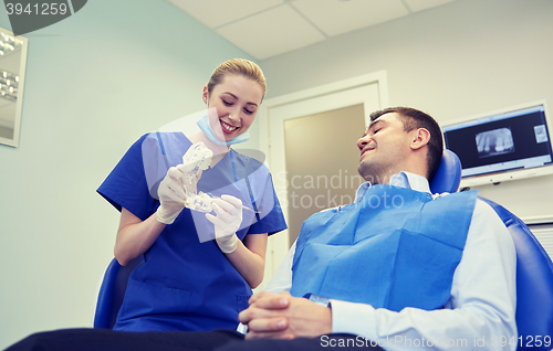 Image of happy dentist showing jaw layout to male patient