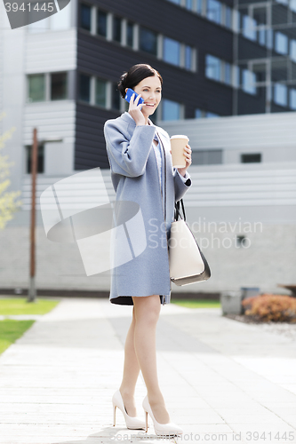 Image of happy businesswoman calling on smartphone in city 